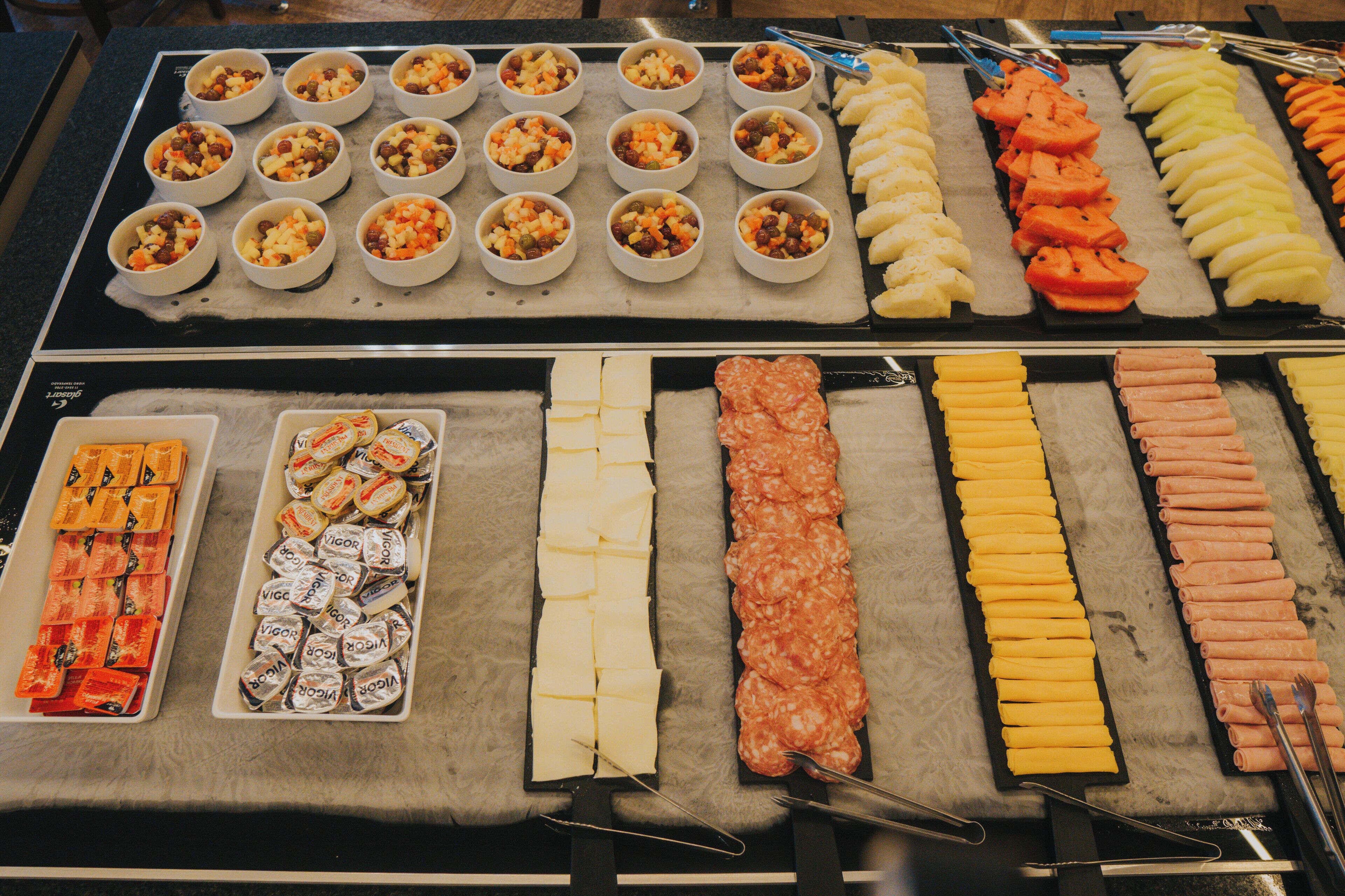 Un bufé con diversas opciones de comida, incluyendo frutas, quesos y carnes.