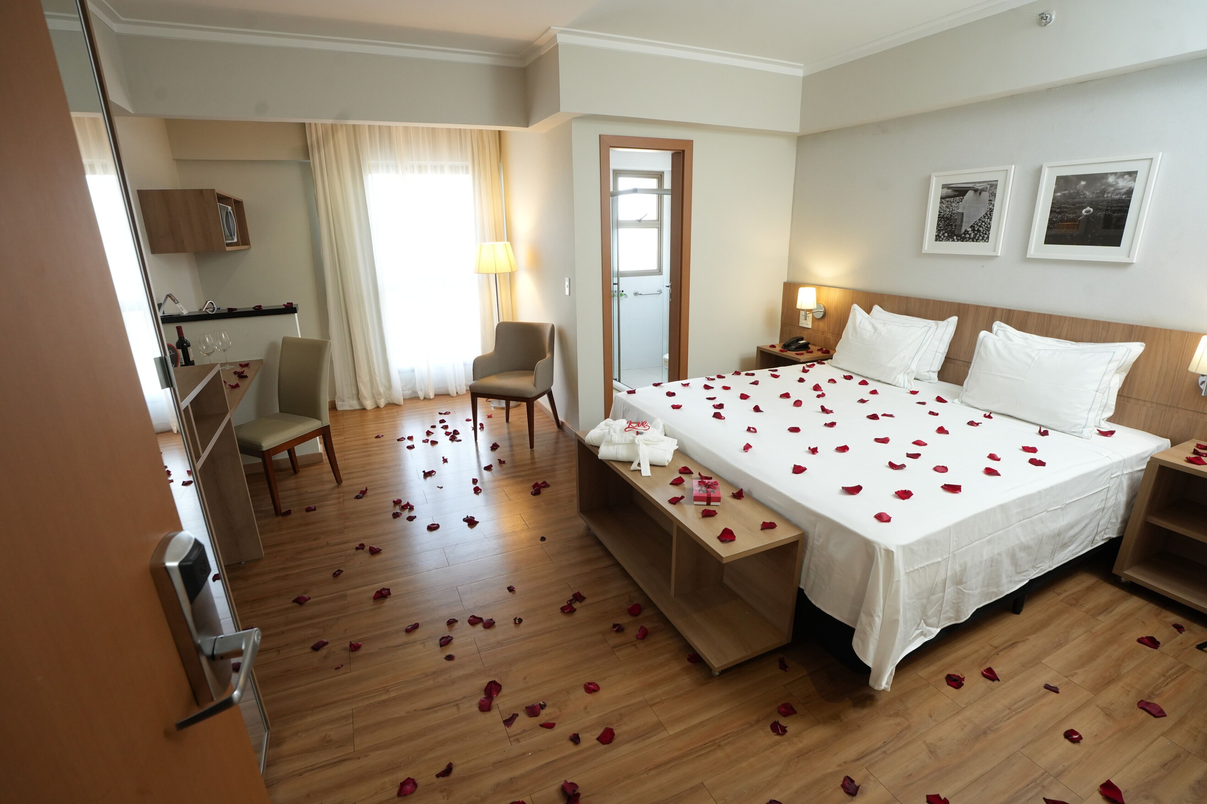 Una habitación de hotel con cama, escritorio, silla, espejo y puerta.