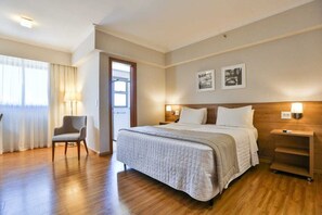 A hotel room with a large bed, a chair, a nightstand, and a window with curtains. -  Matiz Vilaboim Ribeirão Preto (Ribeirão Preto)