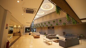 A modern lobby with a high ceiling, recessed lighting, and a seating area with sofas and a coffee table. -  Matiz Vilaboim Ribeirão Preto (Ribeirão Preto)