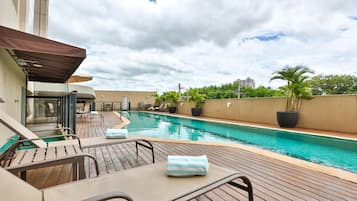 Una piscina al aire libre, sombrillas, sillones reclinables de piscina