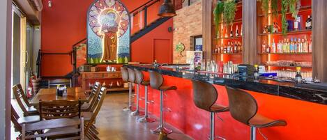 A bar area with a red counter, bar stools, and a decorative stained glass window.