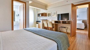 Hotellihuone, jossa on sänky, työpöytä tuolilla, televisio ja vaatekaappi.