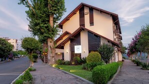 Un hotel moderno con un diseño arquitectónico único, que presenta un techo inclinado y un jardín bien cuidado.