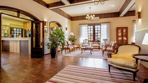 Un hall espacioso con piso de madera, un tapete a rayas y varias zonas de estar, incluyendo un sofá y sillones.