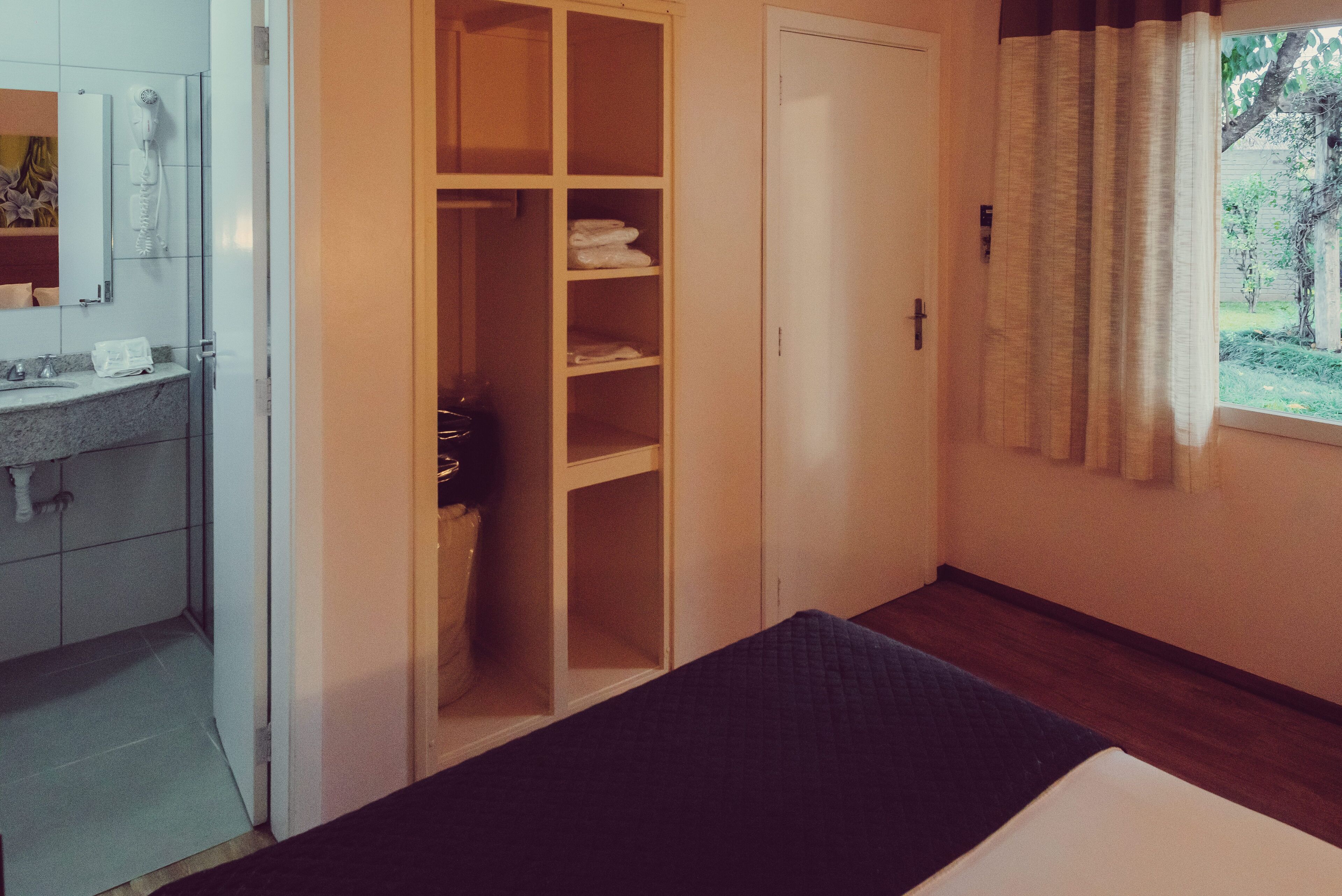 A bedroom with a bed, a wardrobe, and a bathroom with a sink and mirror.