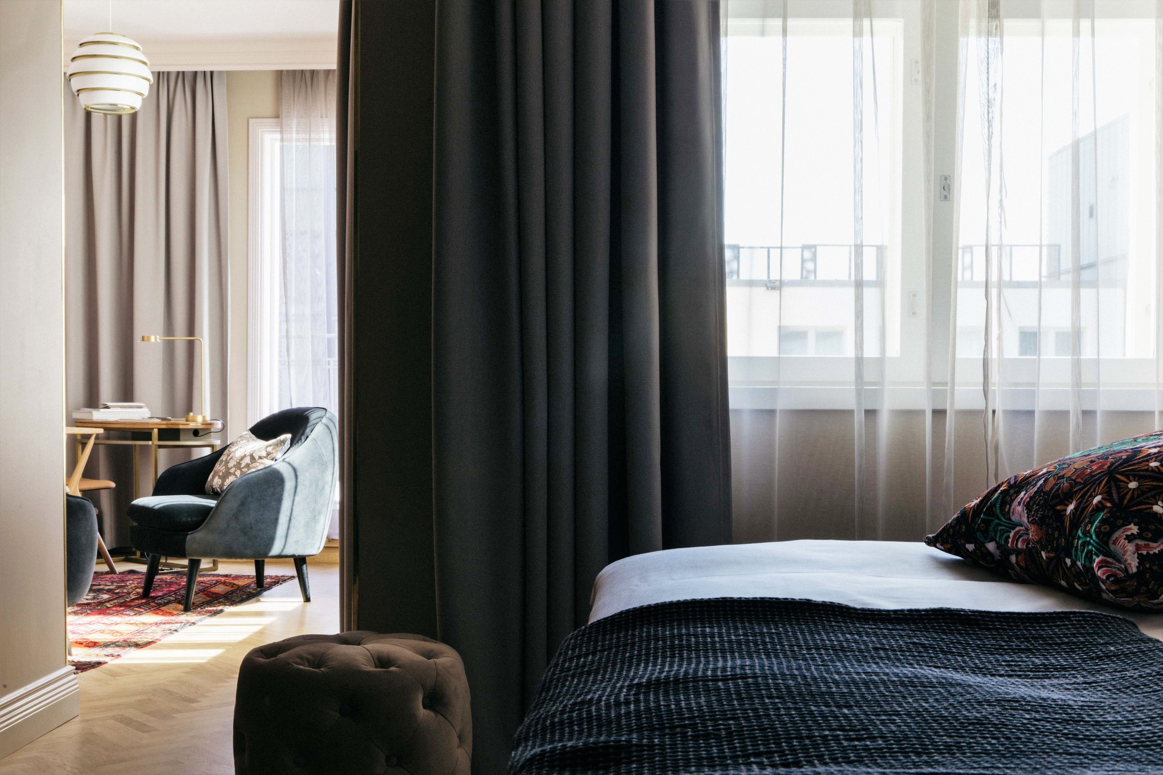 A hotel room with a bed, a chair, a desk, and a view of the outside.