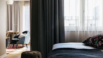 A hotel room with a bed, a chair, a desk, and a view of the outside.