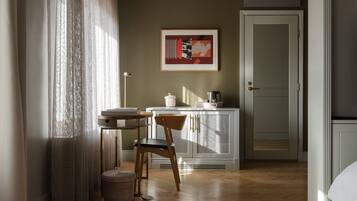 A room with a wooden floor, a chair, a table, a cabinet, a door, and a framed picture on the wall.