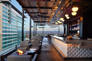 A rooftop bar with outdoor seating, a bar counter, and a fire feature. - AC Hotel by Marriott Denver Downtown (Denver)