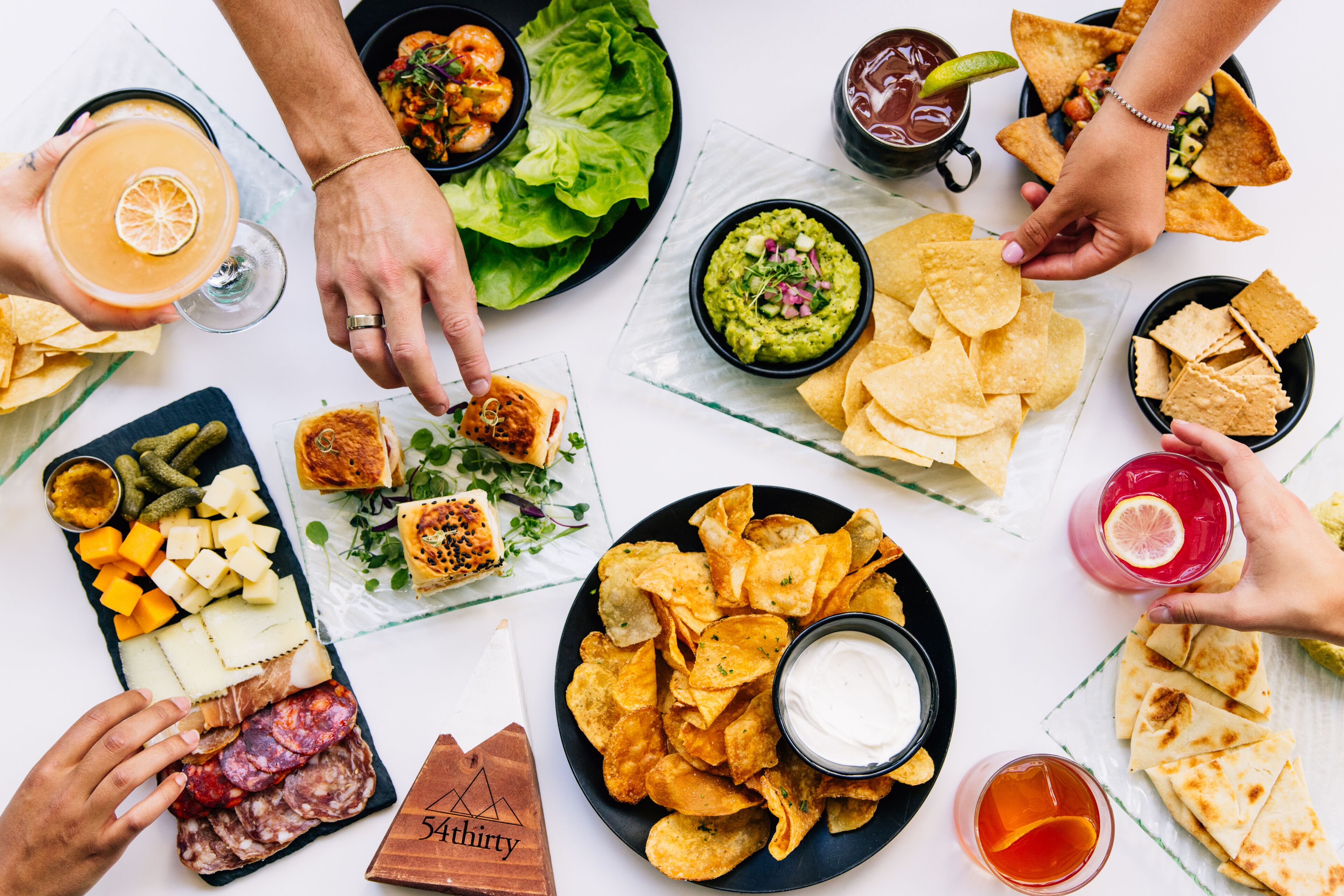 A table with various food items including chips, dips, and a charcuterie board.