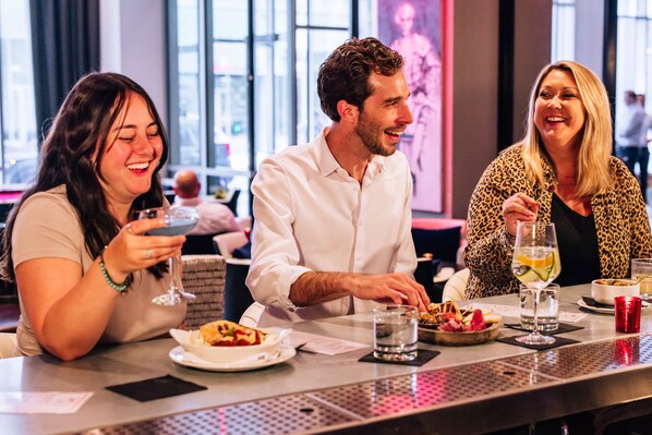 Un comedor con mesas, sillas y vistas de la ciudad a través de grandes ventanales.