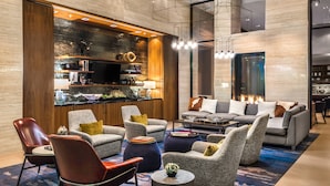 A modern living room with a sofa set, armchairs, and a coffee table. There is a fireplace and a television on a wooden cabinet.