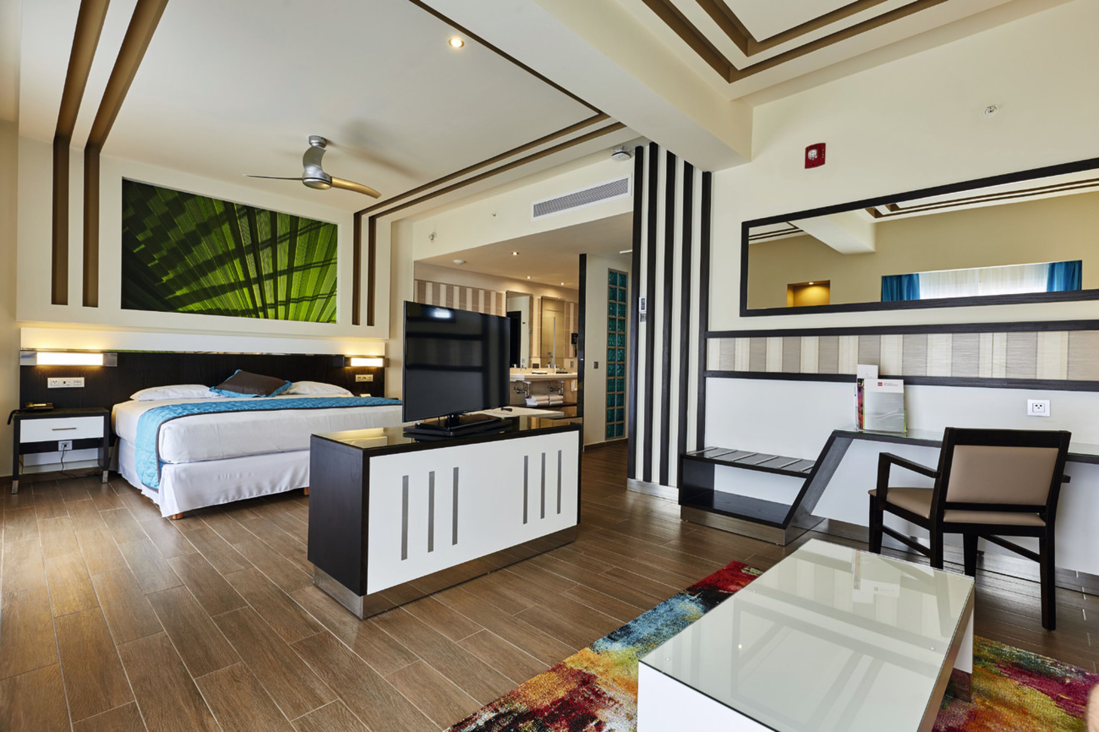 A modern hotel room with a bed, desk, and a large mirror.