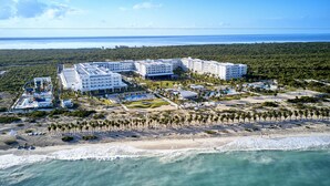 Une vue aérienne d’un complexe hôtelier comprenant plusieurs bâtiments, une plage et une vue dégagée sur l’océan.