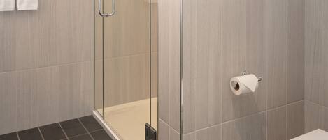 Un baño moderno con cabina de ducha de vidrio, inodoro y perchero.