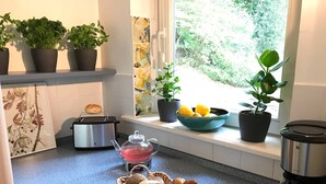 Una cocina con tostadora, tetera, un tazón de limones y una cesta de pan.