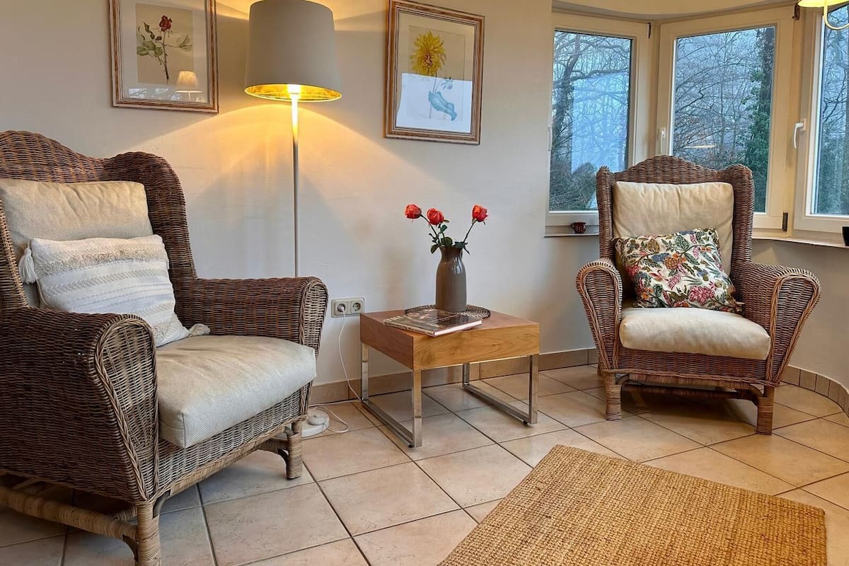 A cozy living room with wicker furniture, a floor lamp, and framed artwork on the walls.