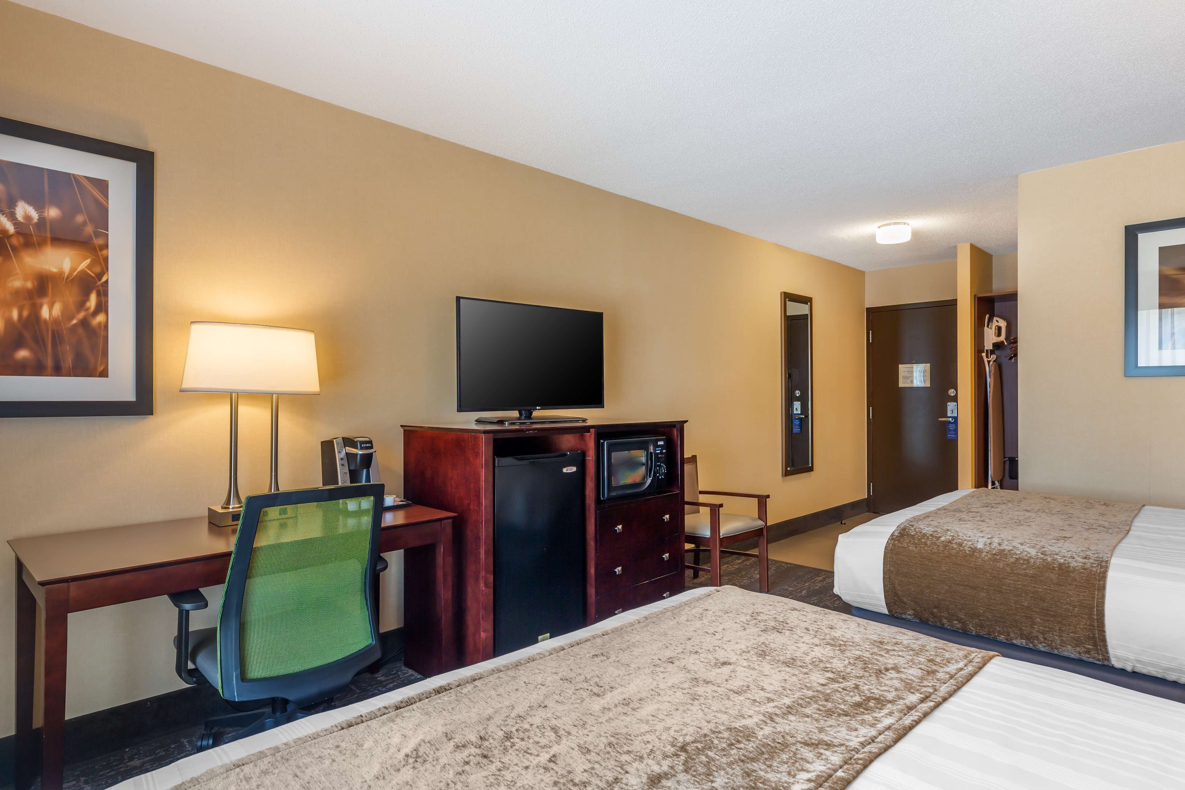 Habitación de hotel con escritorio, televisión, minibar y dos camas.