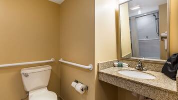A bathroom with a toilet, a sink, a mirror, and a shower stall.