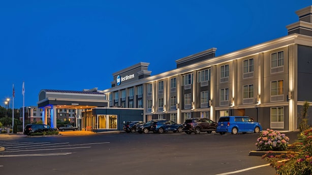 Un hotel Best Western con estacionamiento, varios autos y una entrada bien iluminada.
