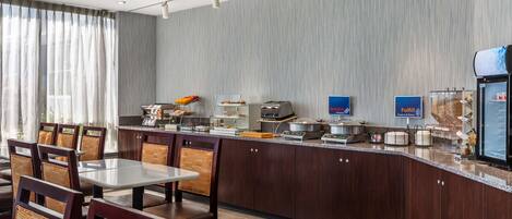 Un área de desayuno moderna con mostrador, asientos y una cafetera.