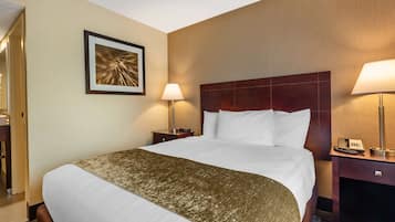 A hotel room with a large bed, two bedside tables, a framed picture on the wall, and a lamp on each table.