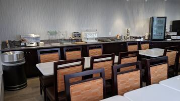 Una barra de desayuno con asientos, una máquina de café y un dispensador de yogur.