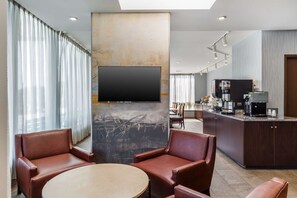 A modern hotel lobby with leather seating, a flat-screen TV, a coffee machine, and a bar area. - Best Western Braintree Inn (Braintree)
