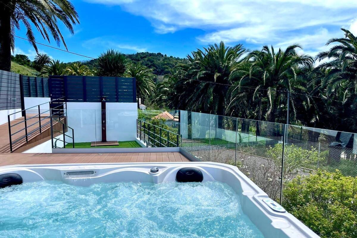 A hot tub with a view of a lush garden and a modern building.