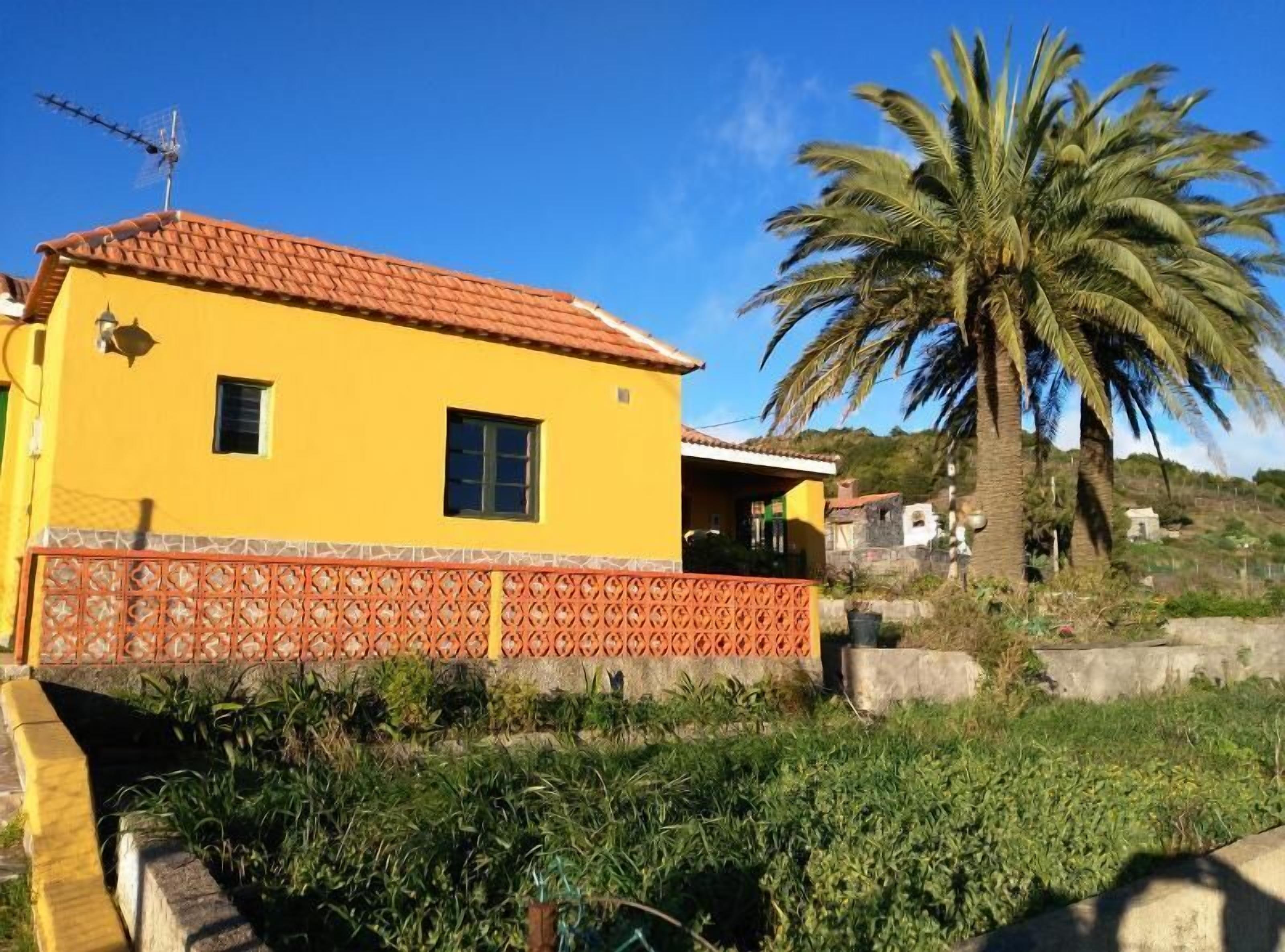 A yellow building with a tiled roof, a small window, and a decorative fence.
