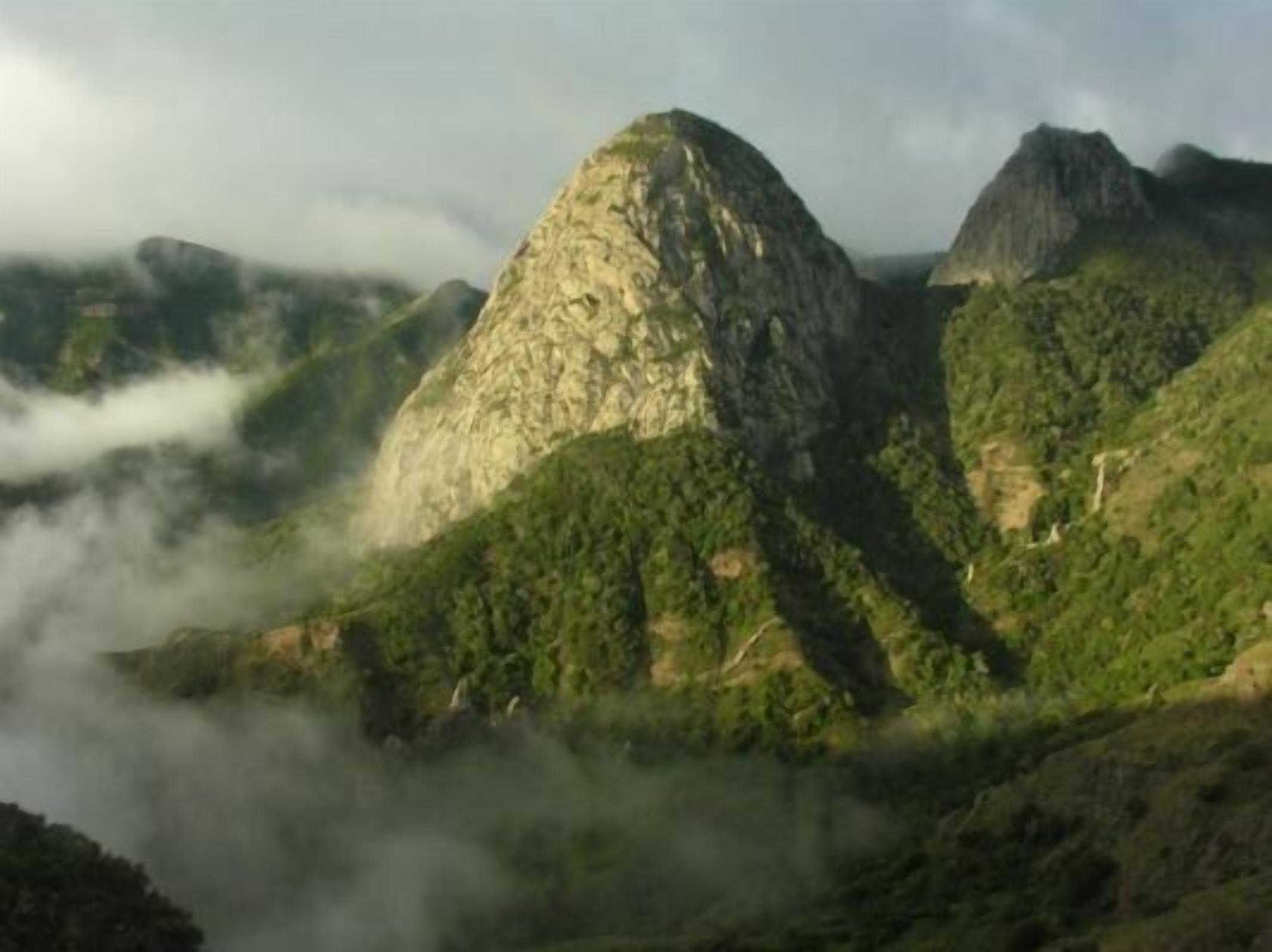Un paisaje montañoso con terreno accidentado y vegetación verde densa.