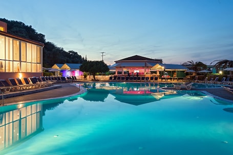 Una piscina al aire libre, sombrillas, sillones reclinables de piscina