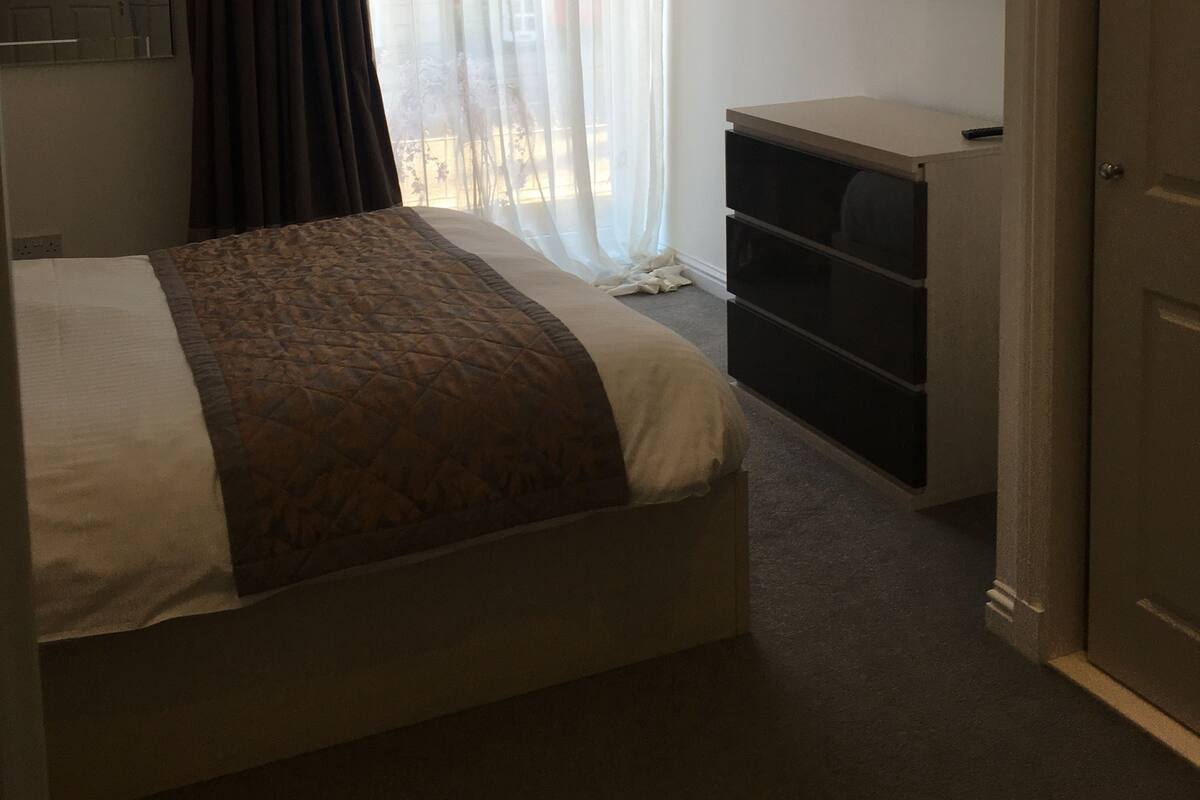 Hotellihuone, jossa on sänky, työpöytä, televisio ja ovi.