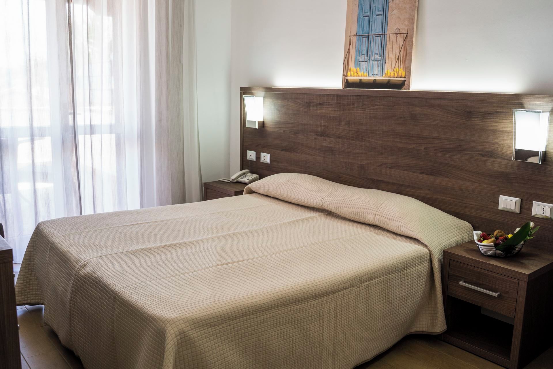 Une chambre d’hôtel avec un grand lit, des tables de chevet, un téléphone et une petite plante.