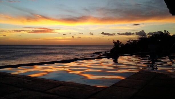 A sunset view from an infinity pool with a clear sky and distant mountains. - Casa Mallen - La Boquita (Diriamba)