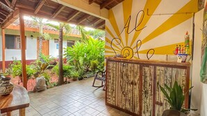 An outdoor patio area with wooden flooring, a central bar with a sun design on the wall, and various plants. - Al Sole Guesthouse (León)