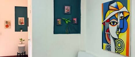 Una habitación con una cama, una pared con obras de arte enmarcadas y una planta en maceta.