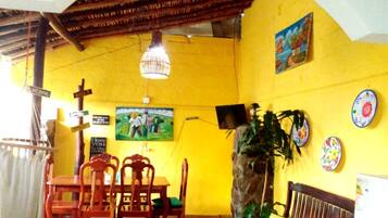 A room with a yellow wall, wooden furniture, a cross, and a painting.