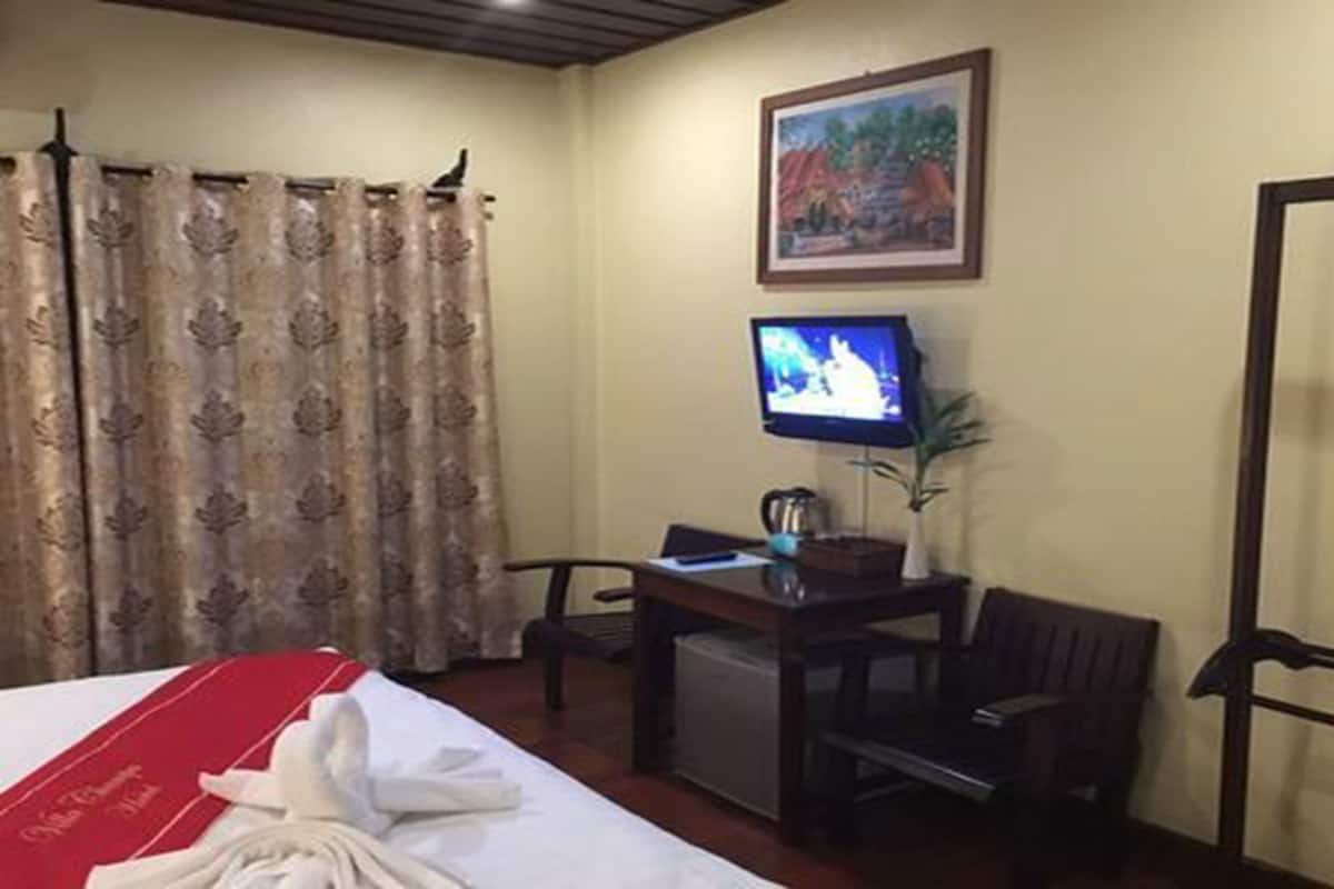 Habitación de hotel con cama, escritorio, silla, televisor y un cuadro en la pared.