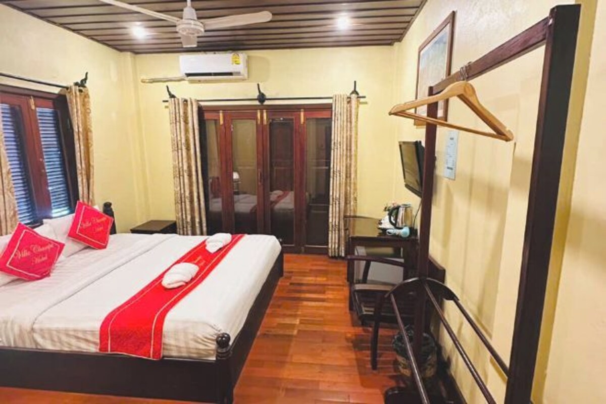 Una habitación de hotel con cama, escritorio, silla, televisor y armario.