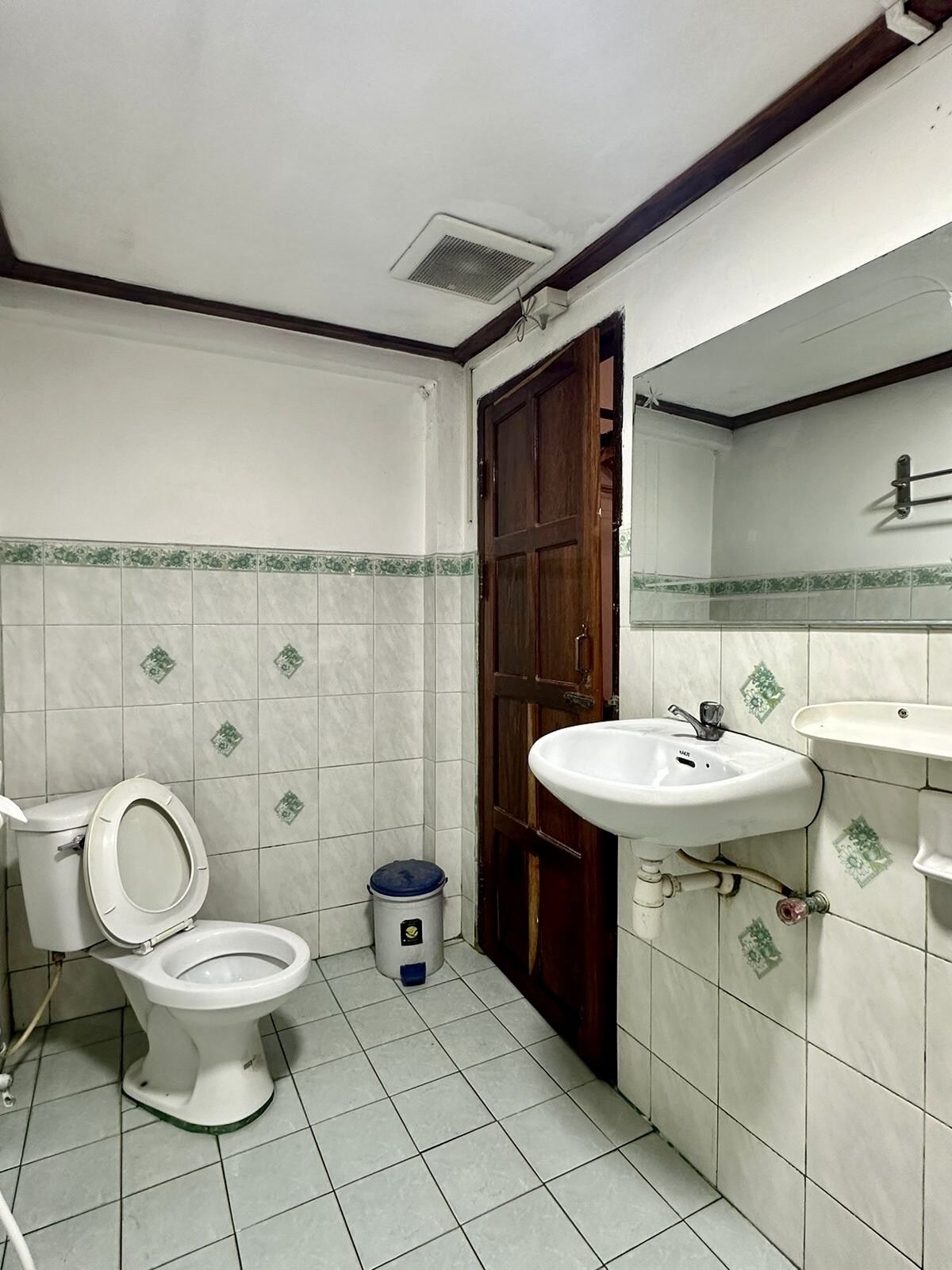 A small bathroom with a toilet, a sink, and a mirror.