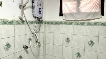 Un baño pequeño con ducha, inodoro y ventana con cortina.