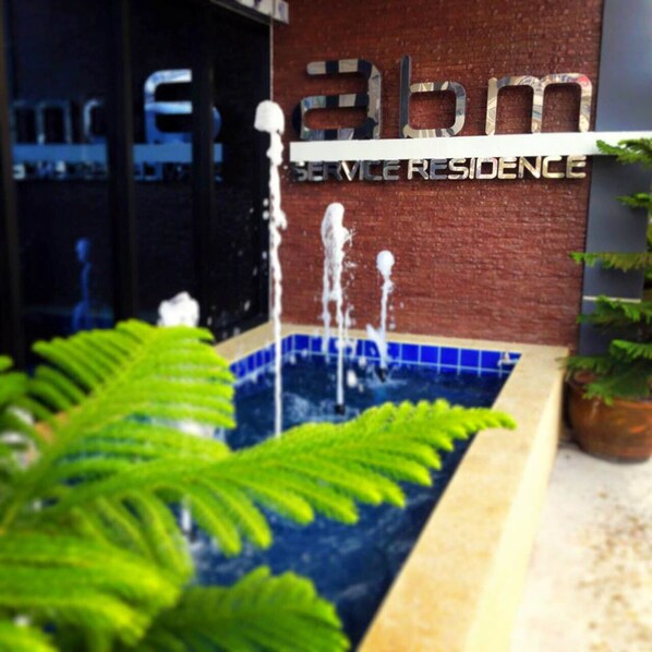 A water feature in front of a building with a sign that reads "Service Residence".