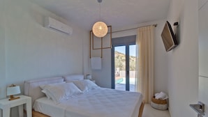Un dormitorio moderno con cama, mesita de noche, lámpara y vistas al exterior.