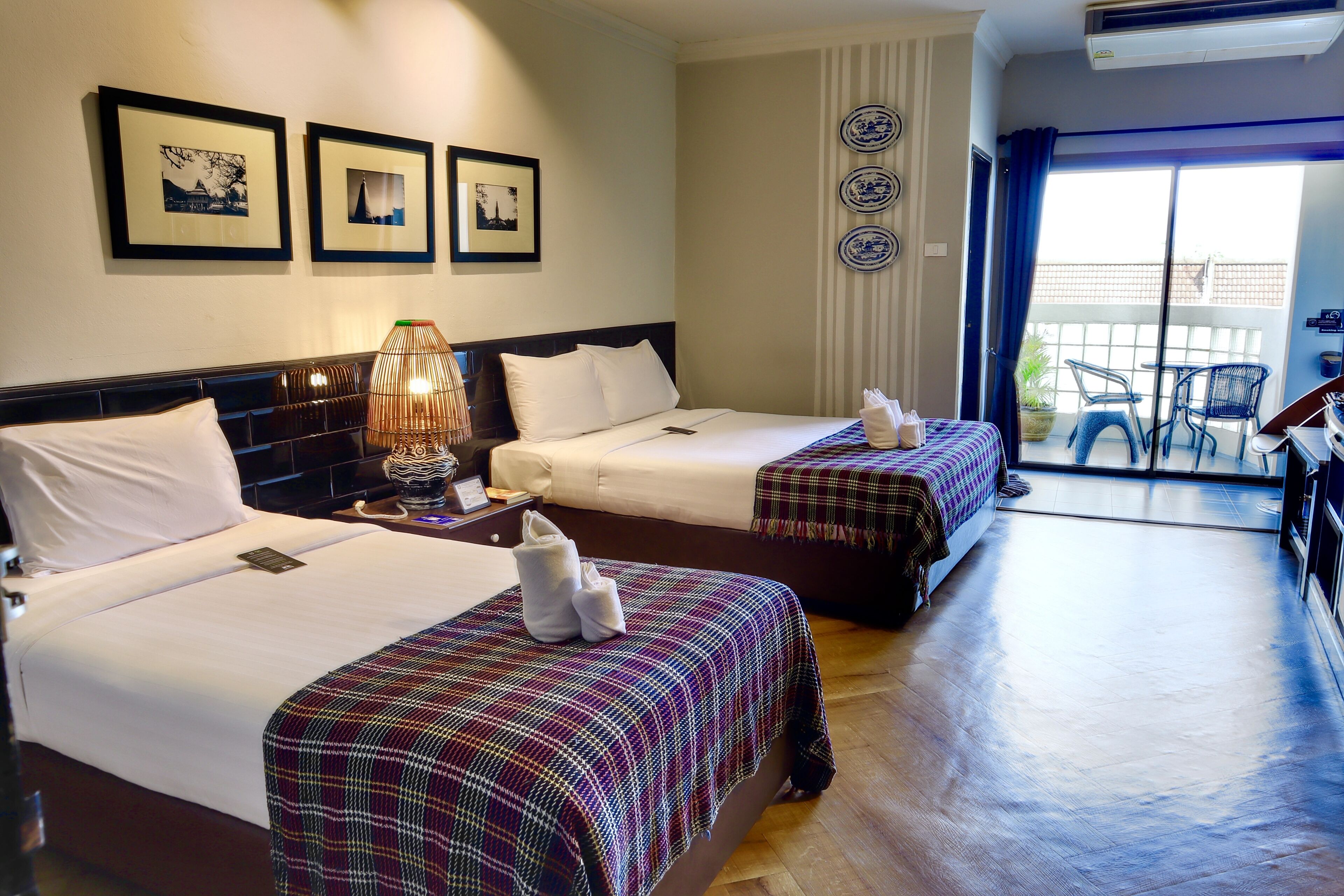 Een hotelkamer met twee bedden, een balkon en een eethoek.