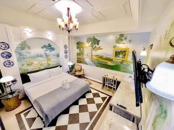 Una habitación de hotel con cama, escritorio, silla, candelabro y un mural en la pared.