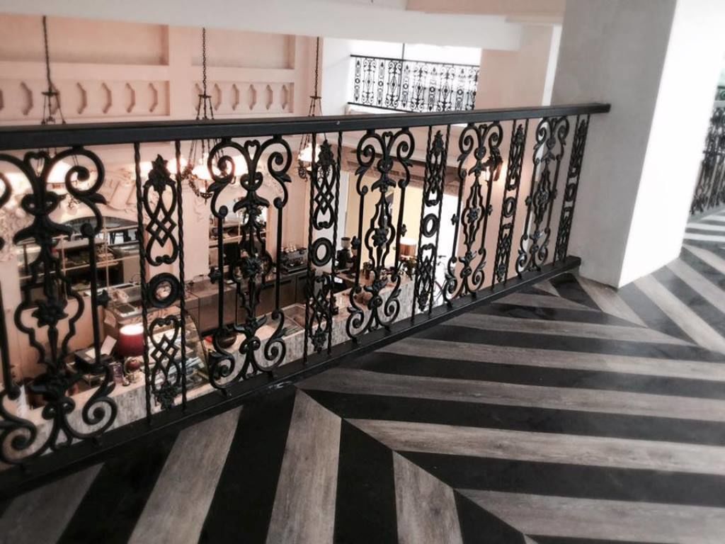A staircase with a black and white striped floor and ornate black metal railings.