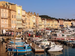 A marina with boats docked, surrounded by buildings with balconies and shops.