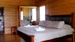 Una habitación con paneles de madera, una cama, un espejo y una mesita.
